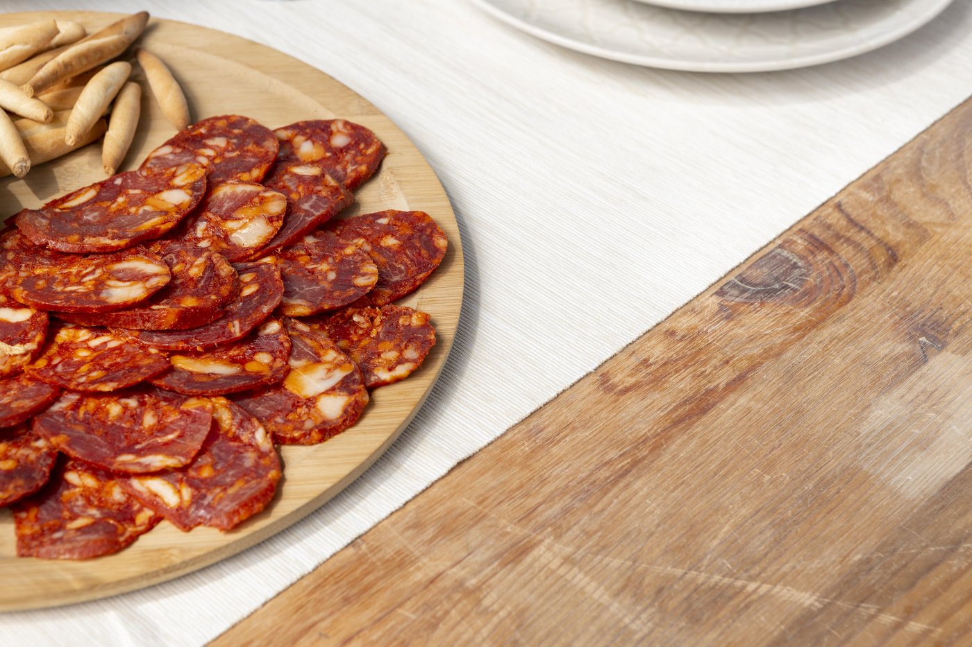 Chorizo ib&eacute;rico loncheado en rodajas servido en un plato de madera